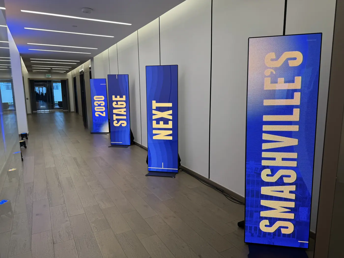 Free-standing all-in-one LED displays lined up in an event hallway