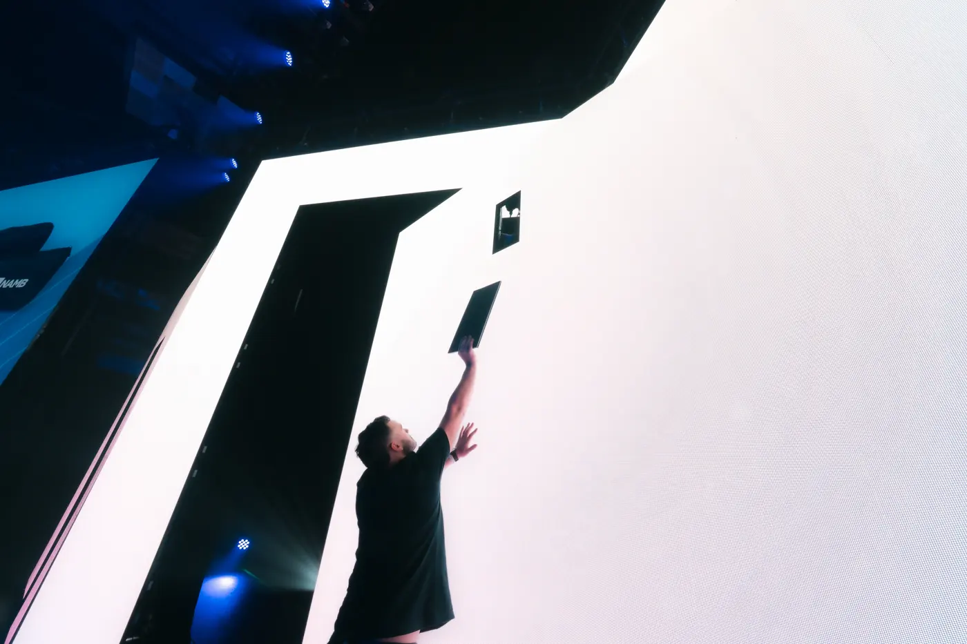 Crew member reaching up to adjust a large white LED wall during build