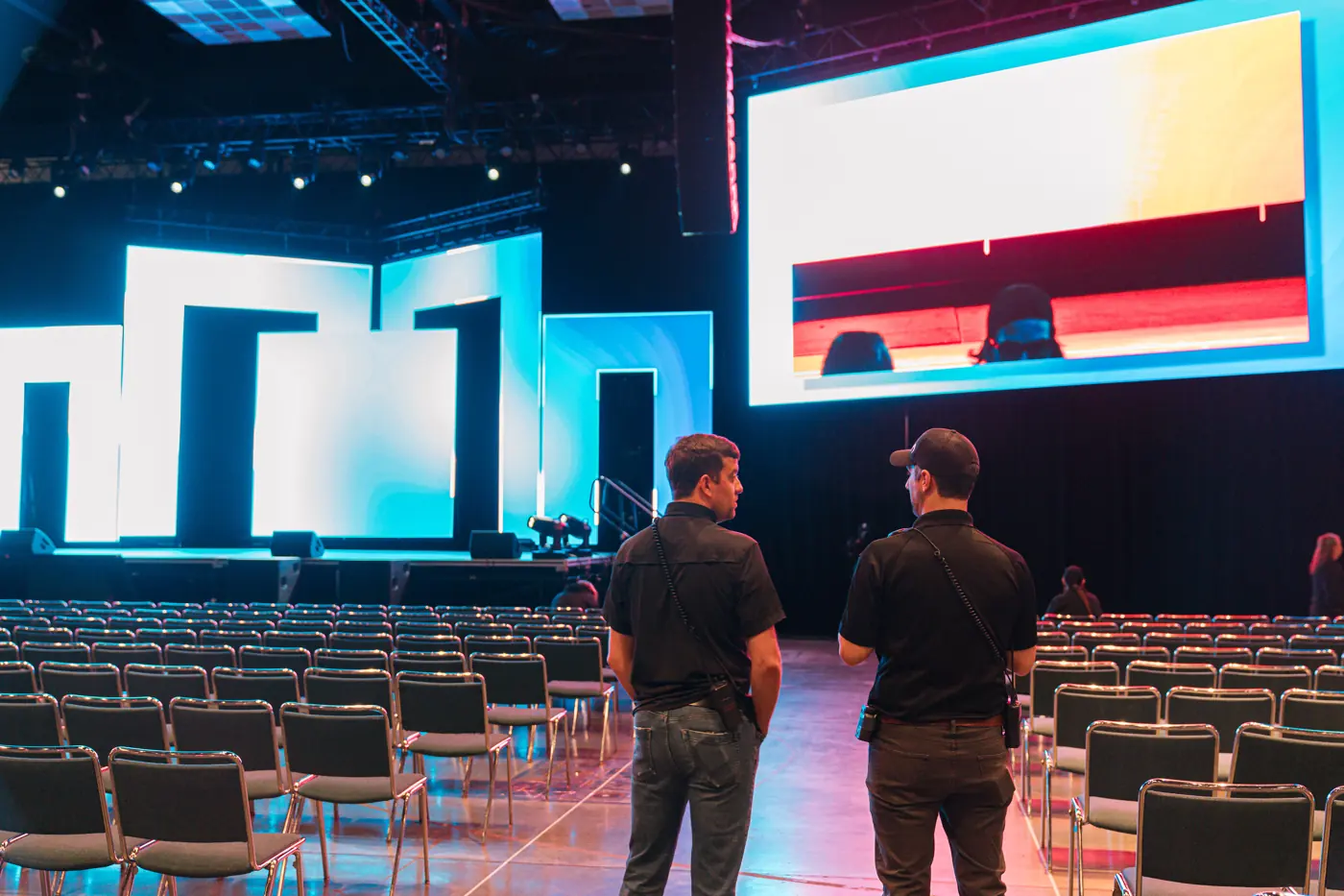 Two crew members checking a stage with large LED walls before a general session