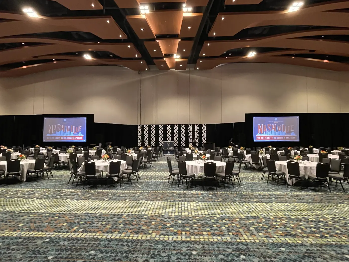 Dinner setup with stage screens in the Music City Center ballroom
