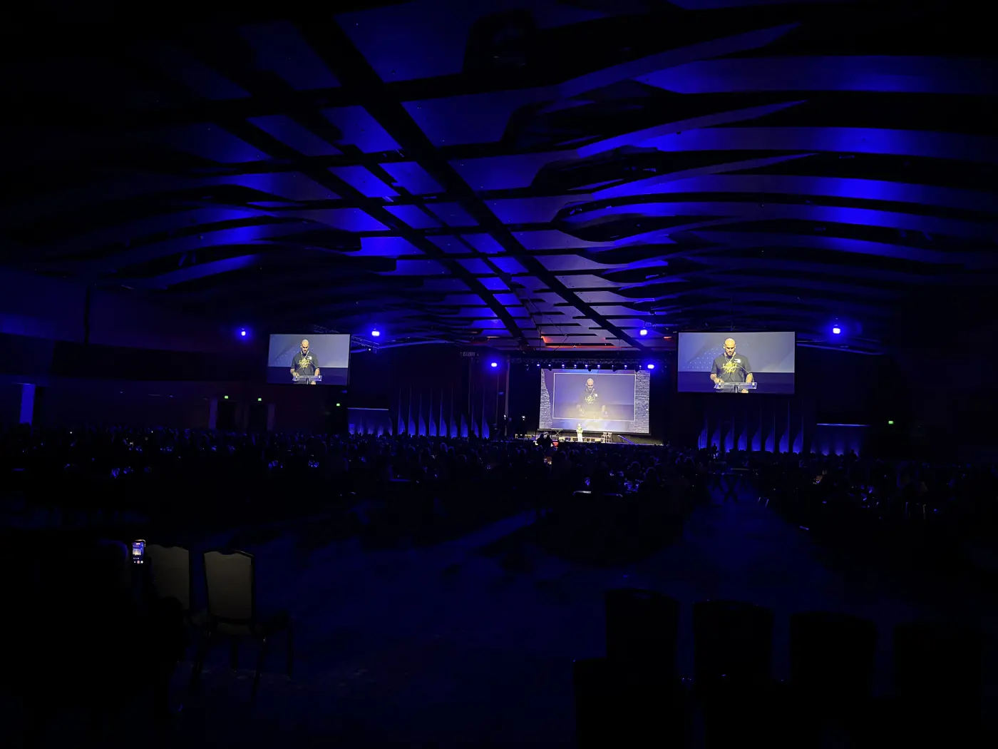 Speaker on stage and screens in the Music City Center ballroom